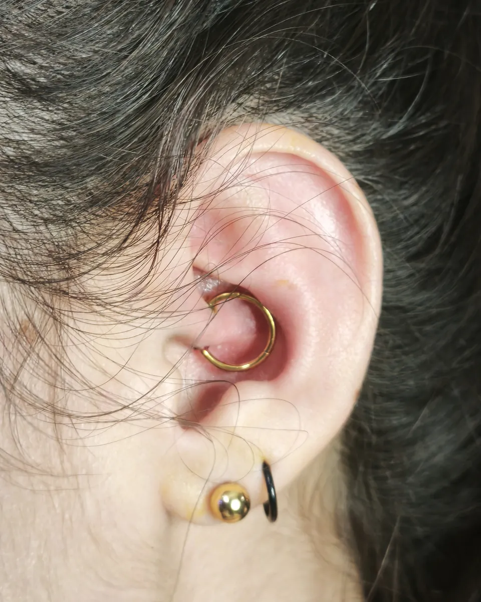 Aro dorado en el helix de la oreja y una joya en el lóbulo