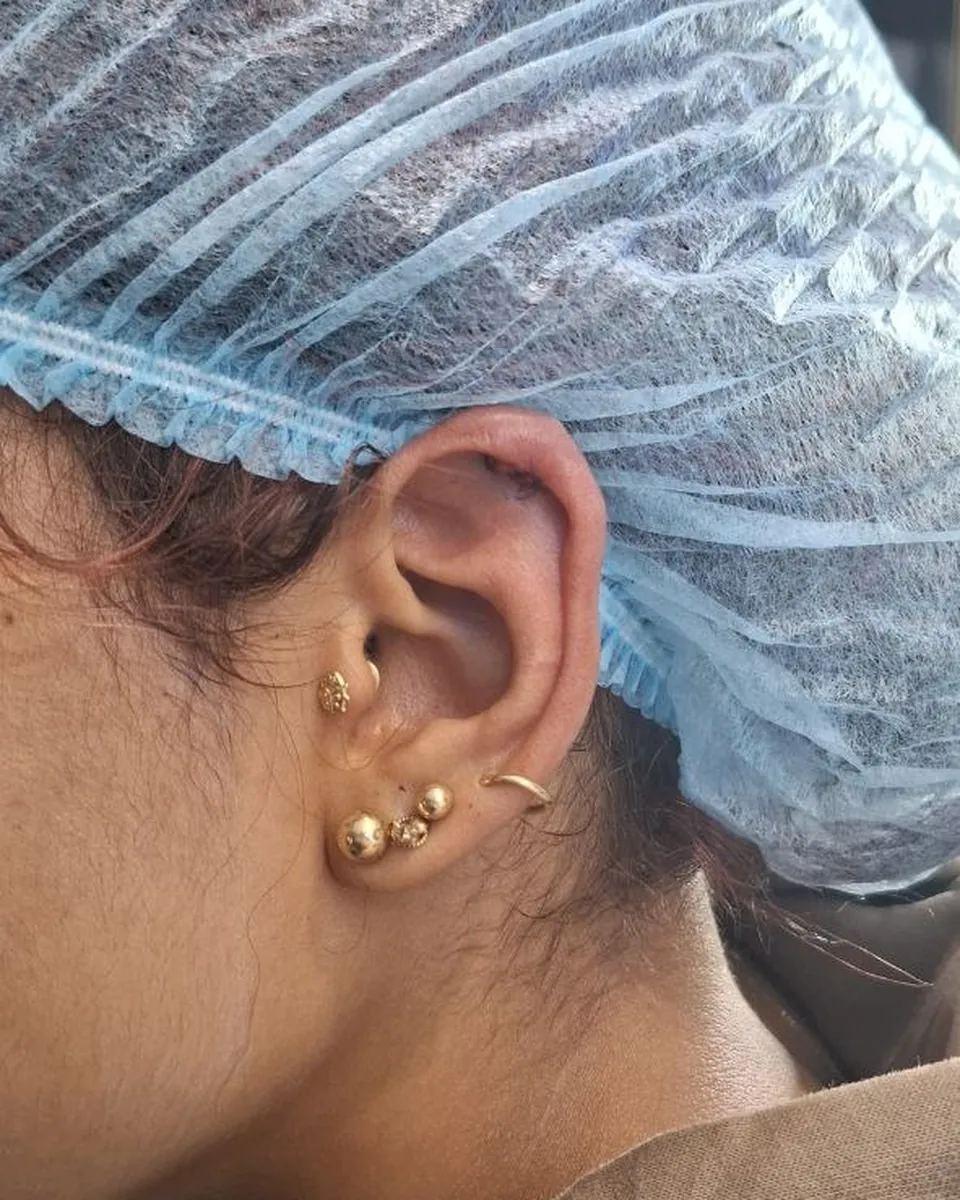 Lóbulo con dos joyas doradas y una perforación en el cartílago