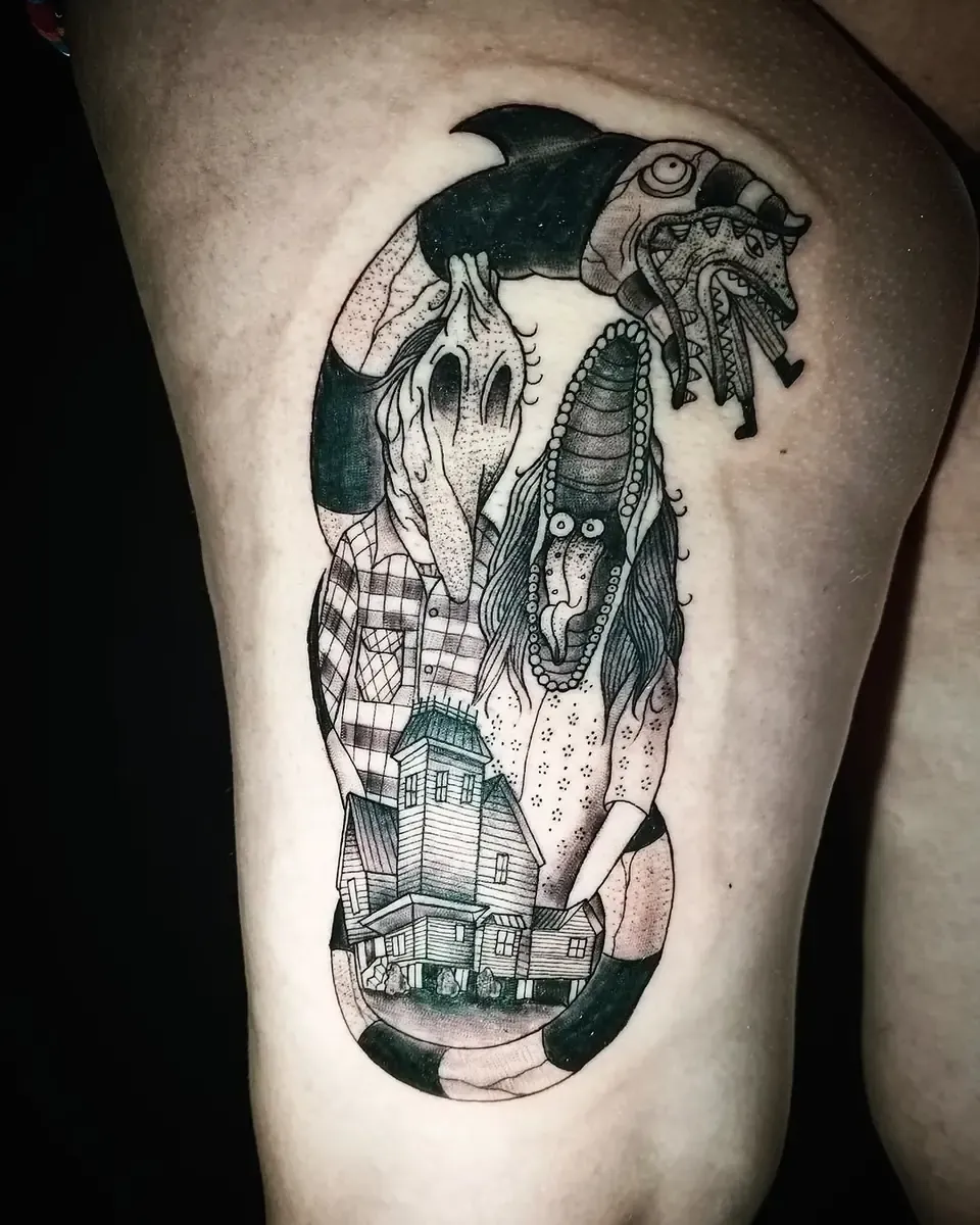 Tatuaje en black and grey inspirado en Beetlejuice, con el gusano de arena y la casa, en el muslo